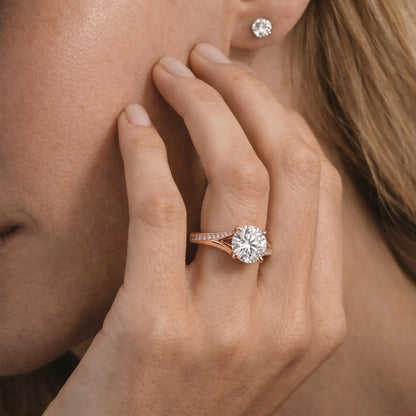 Close-up of a hand wearing a rose gold ring with a diamond, touching the cheek.
