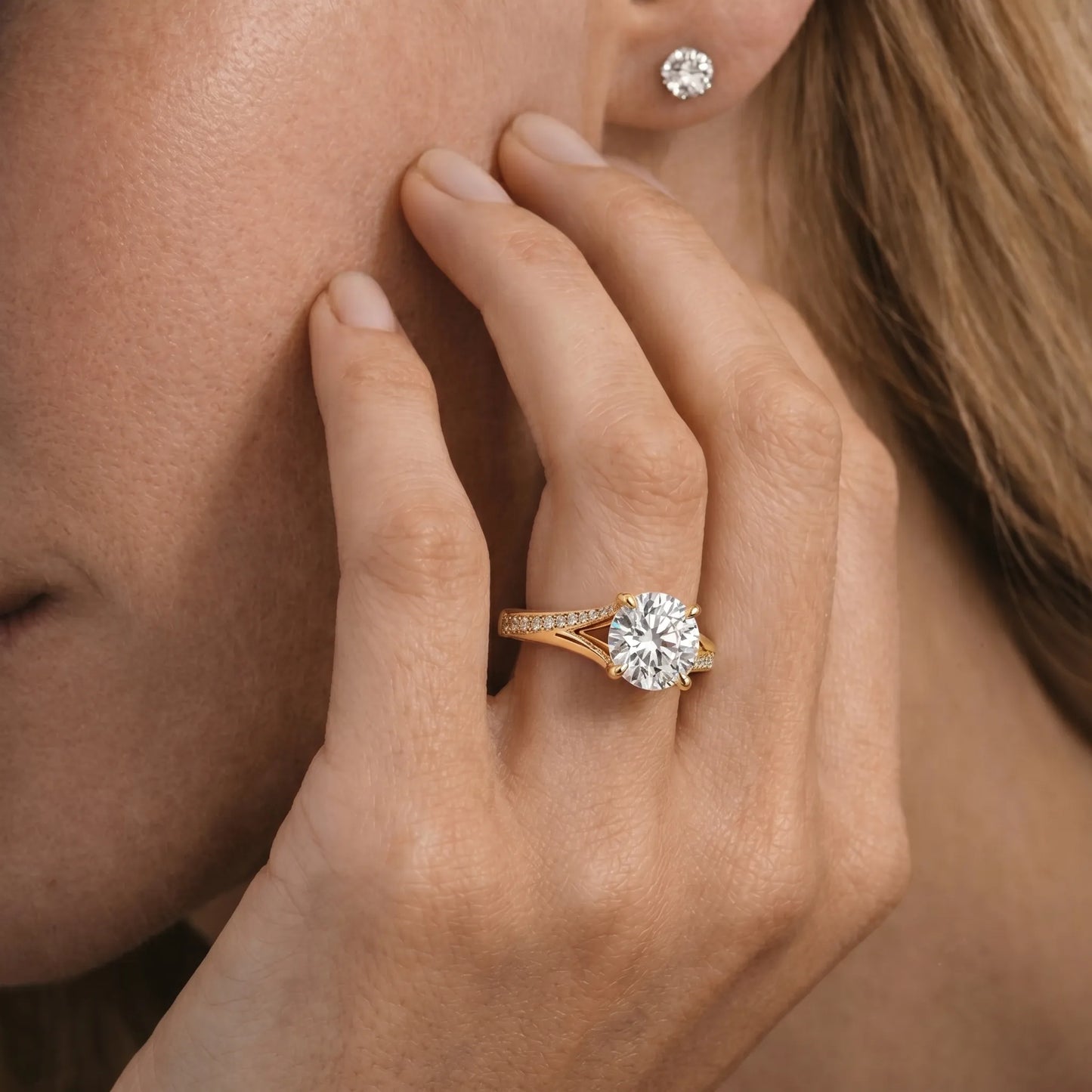 yellow gold Close-up of a hand wearing a diamond ring with an earring.