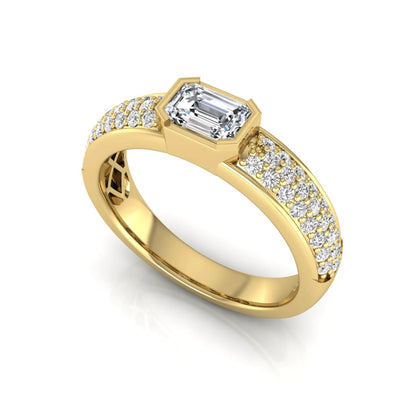 Bezel set emerald cut lab grown diamond engagement ring featuring a 0.52 carat emerald center diamond with pavé round diamond band in yellow gold.