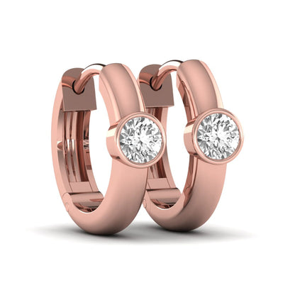 Bezel set round cut lab grown diamond huggie hoop earrings featuring a hinged snap closure and polished rose gold design.