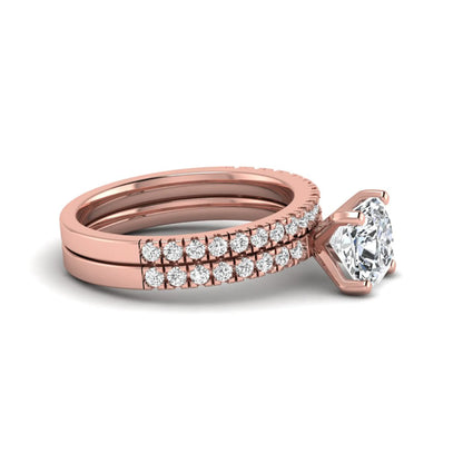 Cushion cut lab grown diamond bridal ring set featuring a four-prong solitaire engagement ring with a matching pavé diamond wedding band in a rose gold tone design.