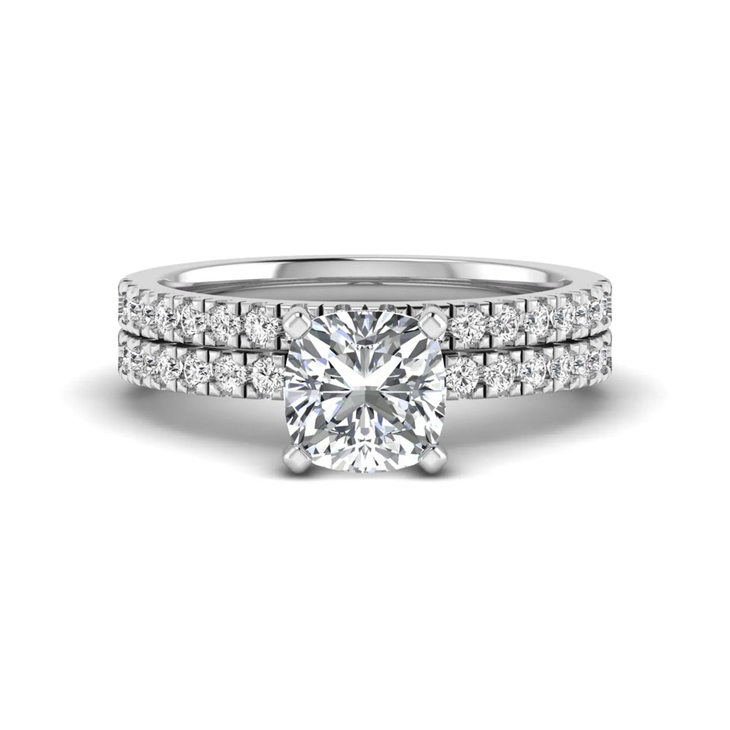 Cushion cut lab grown diamond bridal ring set featuring a four-prong solitaire engagement ring with a matching pavé diamond wedding band in a white gold tone design.