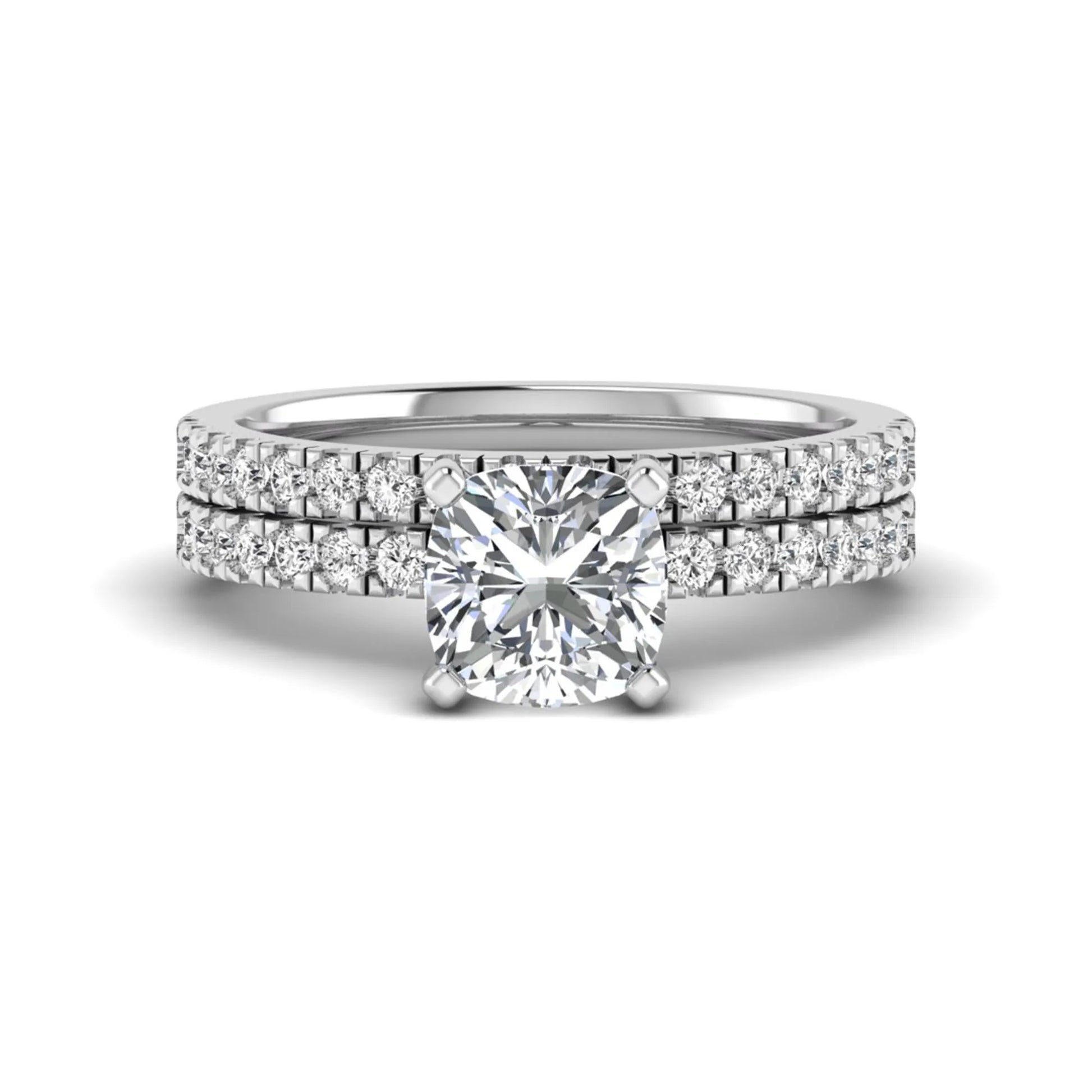 Cushion cut lab grown diamond bridal ring set featuring a four-prong solitaire engagement ring with a matching pavé diamond wedding band in a white gold tone design.