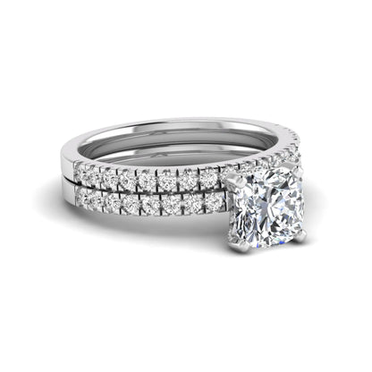 Cushion cut lab grown diamond bridal ring set featuring a four-prong solitaire engagement ring with a matching pavé diamond wedding band in a white gold tone design.