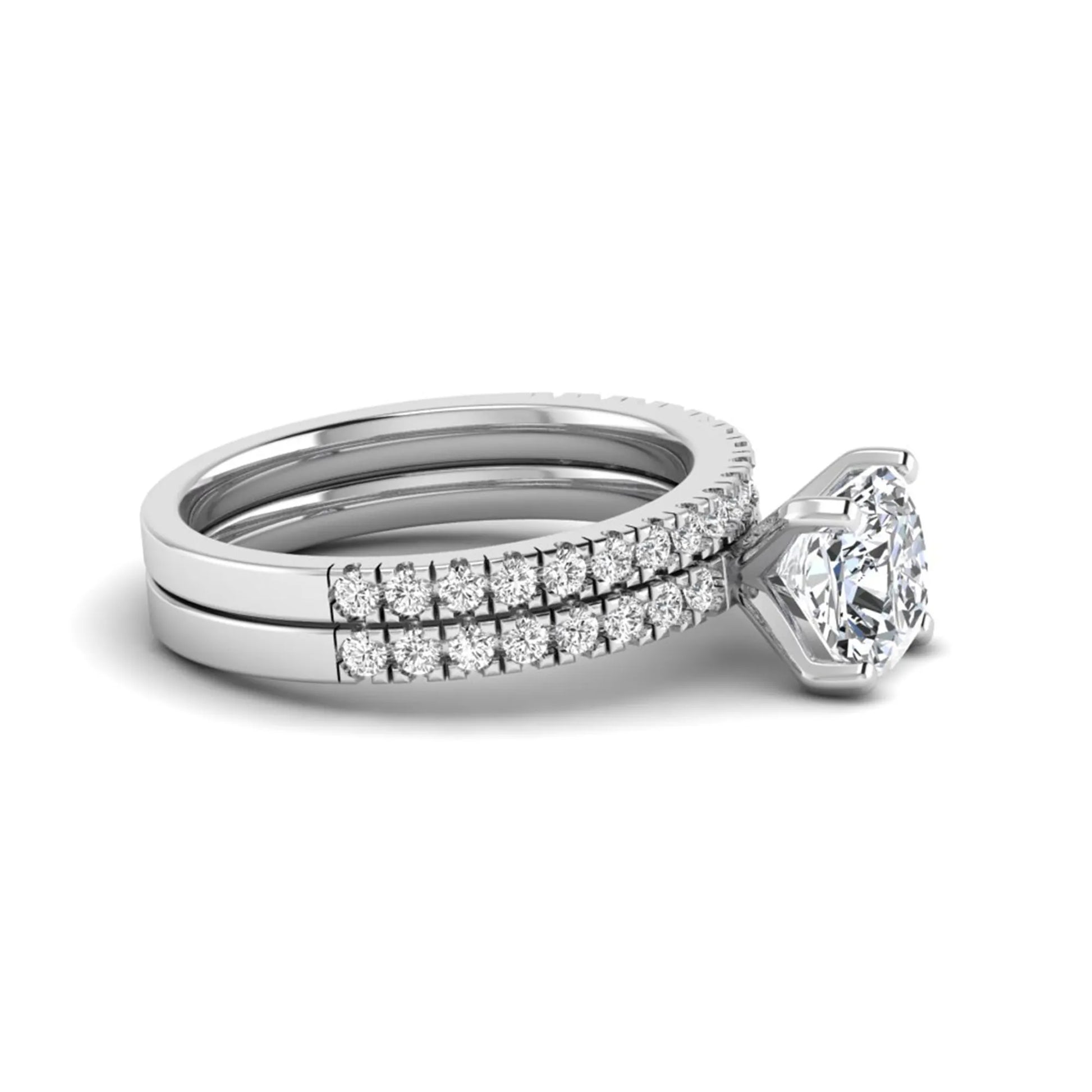 Cushion cut lab grown diamond bridal ring set featuring a four-prong solitaire engagement ring with a matching pavé diamond wedding band in a white gold tone design.
