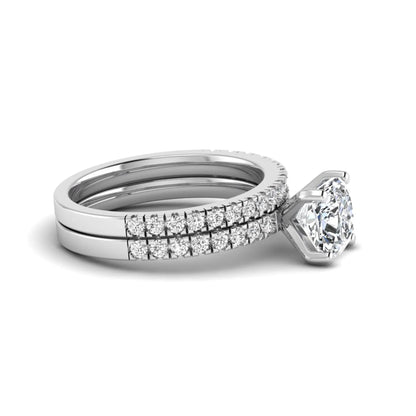 Cushion cut lab grown diamond bridal ring set featuring a four-prong solitaire engagement ring with a matching pavé diamond wedding band in a white gold tone design.