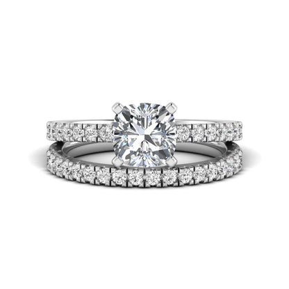 Cushion cut lab grown diamond bridal ring set featuring a four-prong solitaire engagement ring with a matching pavé diamond wedding band in a white gold tone design.