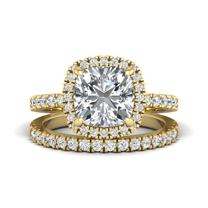 Cushion cut lab grown diamond bridal ring set featuring a halo engagement ring with a matching pavé diamond wedding band in a yellow gold style design.