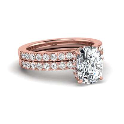 Cushion cut lab grown diamond hidden halo bridal ring set with pavé round diamonds and matching wedding band in a rose gold tone finish.