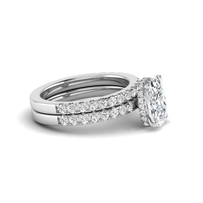 Cushion cut lab grown diamond hidden halo bridal ring set with pavé round diamonds and matching wedding band in a white gold tone finish.