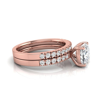 Cushion cut lab grown diamond bridal ring set featuring a four-prong solitaire engagement ring with pavé round diamond accents and matching wedding band in rose gold finish.