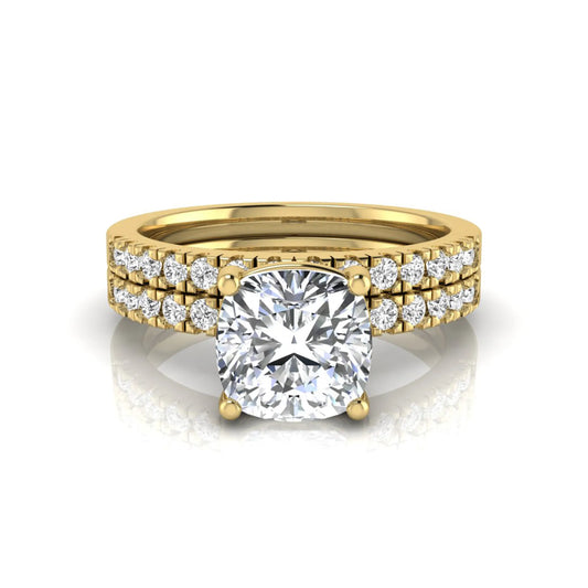 Cushion cut lab grown diamond bridal ring set featuring a four-prong solitaire engagement ring with pavé round diamond accents and matching wedding band in yellow gold finish.