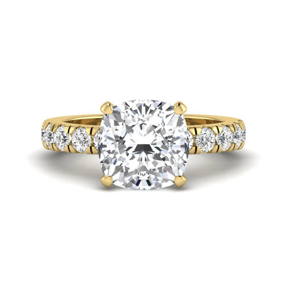 Cushion cut lab grown diamond solitaire engagement ring featuring a four-prong setting with a shared prong round diamond band in a yellow gold tone design.