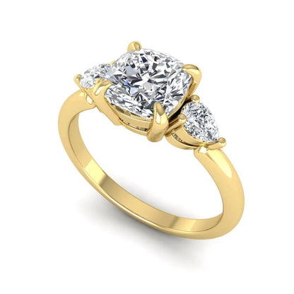 Cushion cut lab grown diamond three stone engagement ring with pear cut side diamonds in a classic prong setting in yellow gold