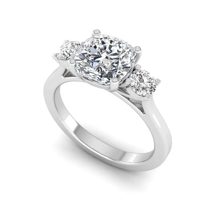 Cushion cut lab grown diamond three stone engagement ring featuring a cushion center diamond with round brilliant side diamonds on a polished white gold band.