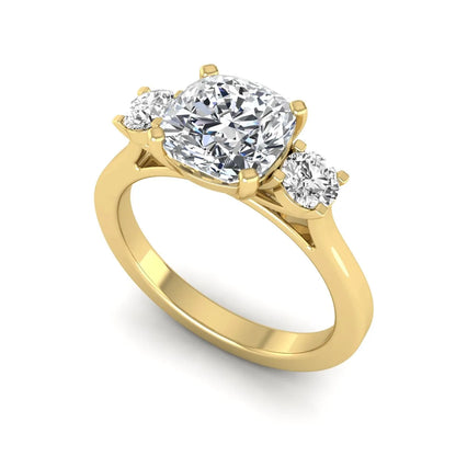 Cushion cut lab grown diamond three stone engagement ring featuring a cushion center diamond with round brilliant side diamonds on a polished yellow gold band.