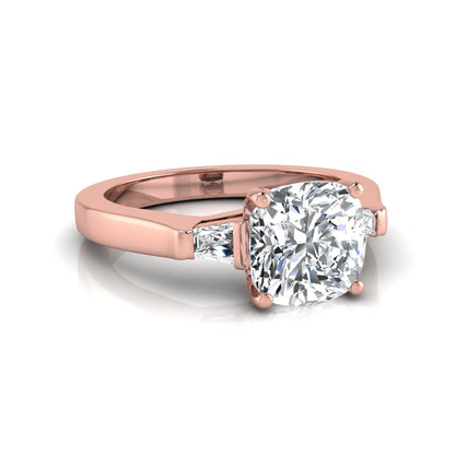 Cushion cut lab grown diamond three stone engagement ring featuring tapered baguette side diamonds in a four prong setting with yellow gold finish. in rose gold