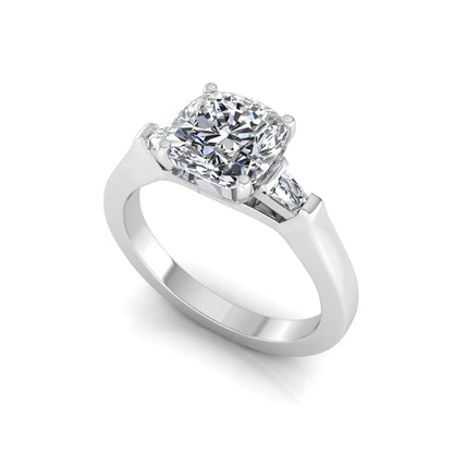 Cushion cut lab grown diamond three stone engagement ring featuring tapered baguette side diamonds in a four prong setting with yellow gold finish. in white gold