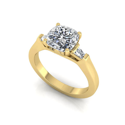 Cushion cut lab grown diamond three stone engagement ring featuring tapered baguette side diamonds in a four prong setting with yellow gold finish. in yellow gold
