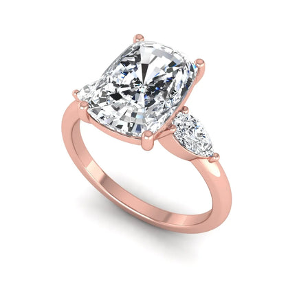Elongated cushion cut lab grown diamond three stone engagement ring featuring pear cut side diamonds in a four-prong setting with a polished rose gold tone band.