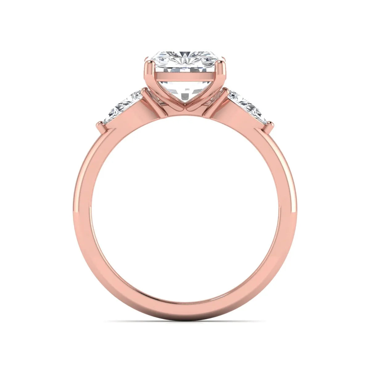 Elongated cushion cut lab grown diamond three stone engagement ring featuring pear cut side diamonds in a four-prong setting with a polished rose gold tone band.