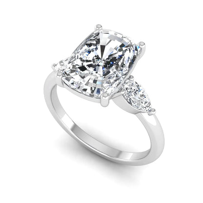 Elongated cushion cut lab grown diamond three stone engagement ring featuring pear cut side diamonds in a four-prong setting with a polished white gold tone band.