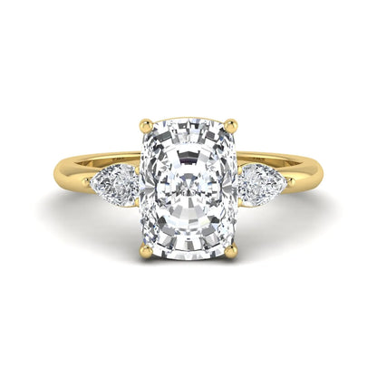 Elongated cushion cut lab grown diamond three stone engagement ring featuring pear cut side diamonds in a four-prong setting with a polished yellow gold tone band.