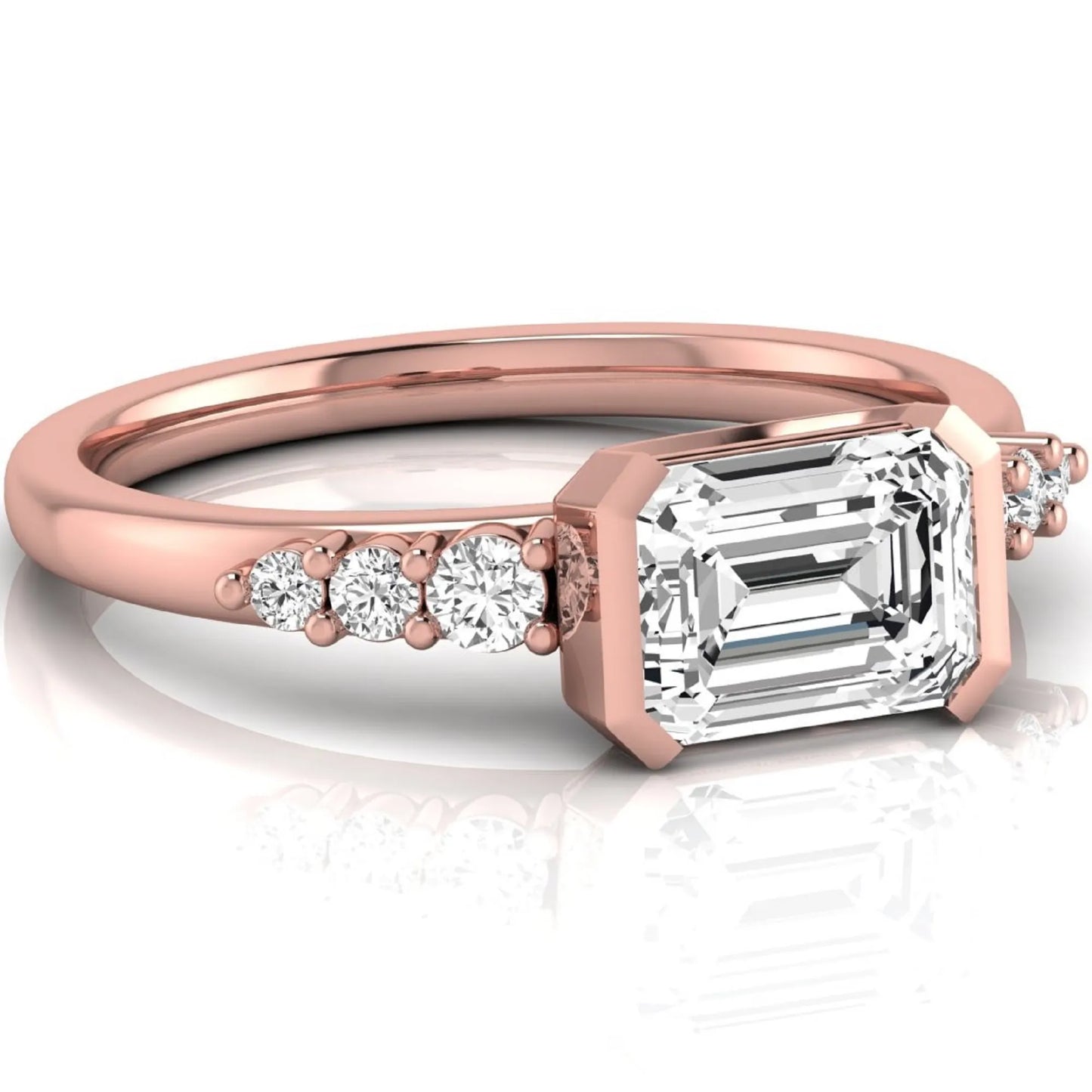 Emerald cut lab grown diamond engagement ring featuring a horizontal east-west bezel-set center diamond with graduated round side diamonds in a rose gold tone.