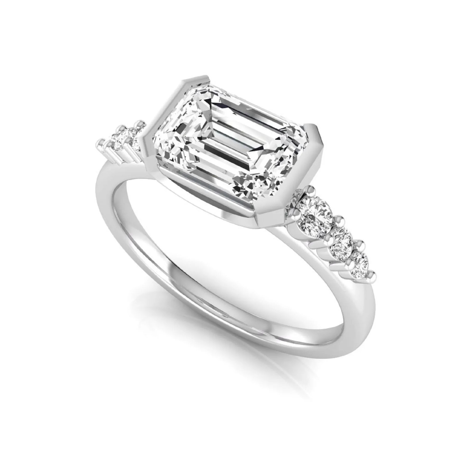 Emerald cut lab grown diamond engagement ring featuring a horizontal east-west bezel-set center diamond with graduated round side diamonds in a white gold tone.