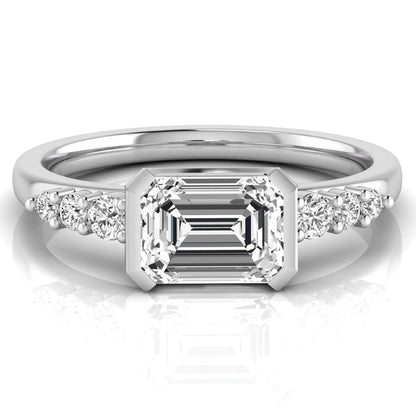 Emerald cut lab grown diamond engagement ring featuring a horizontal east-west bezel-set center diamond with graduated round side diamonds in a white gold tone.