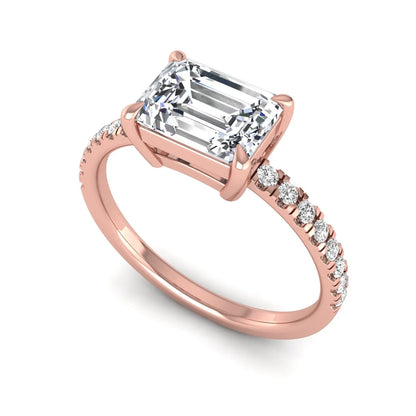 Emerald cut lab grown diamond solitaire pavé engagement ring with four-prong setting and rose gold tone band.