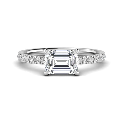 Emerald cut lab grown diamond solitaire pavé engagement ring with four-prong setting and white gold tone band.