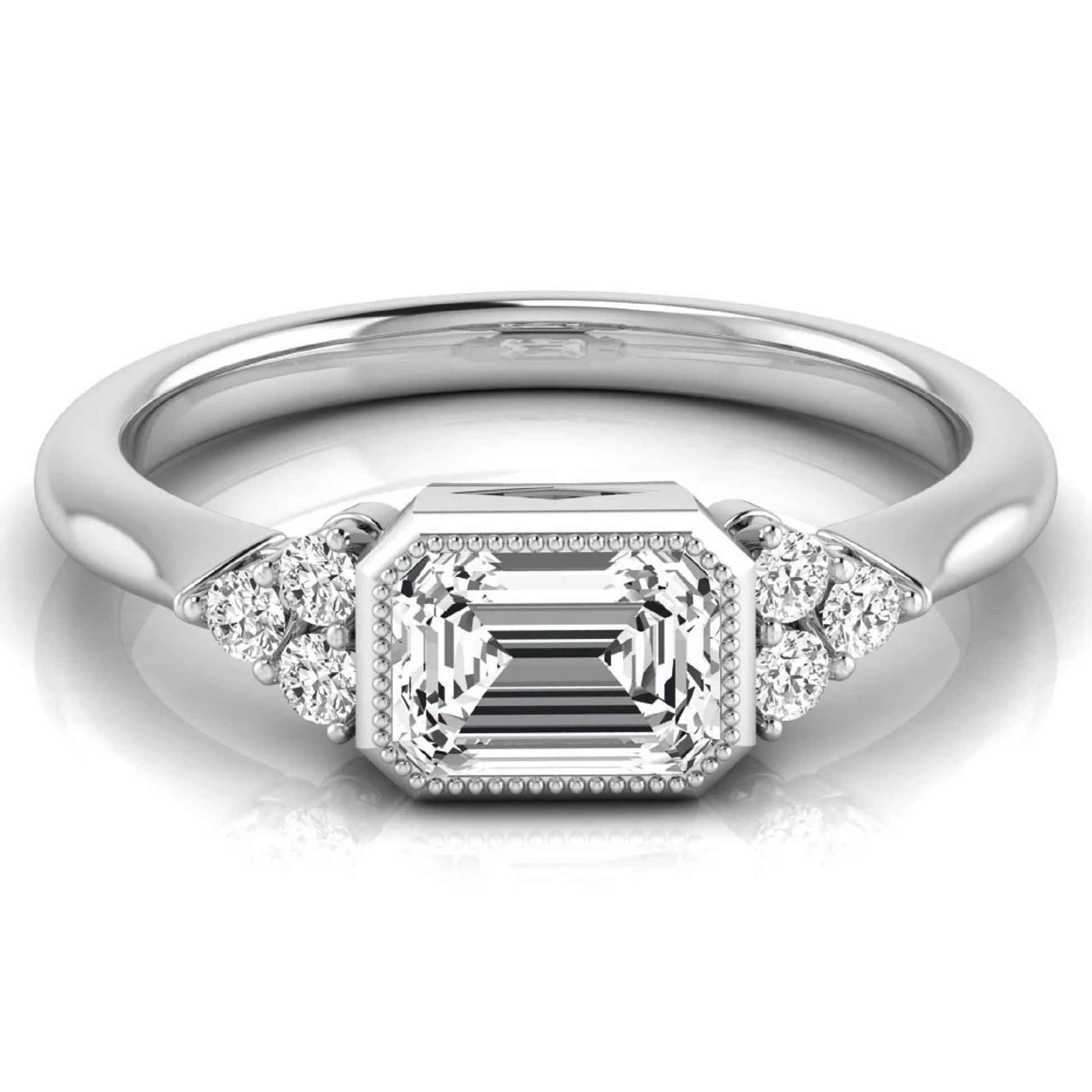 Emerald cut lab grown diamond engagement ring featuring a milgrain bezel setting with round side stone clusters in white gold.
