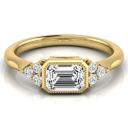 Emerald cut lab grown diamond engagement ring featuring a milgrain bezel setting with round side stone clusters in yellow gold.