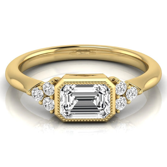 Emerald cut lab grown diamond engagement ring featuring a milgrain bezel setting with round side stone clusters in yellow gold.