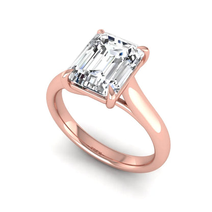 Emerald cut lab grown diamond solitaire engagement ring with a four-prong setting and polished tapered rose gold band.