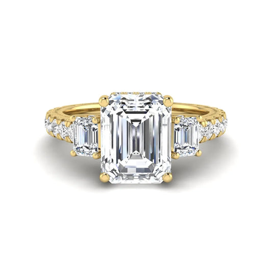 Emerald cut three stone lab grown diamond engagement ring in yellow gold featuring a 2.62 carat IGI certified center diamond with emerald cut side stones and pavé band.