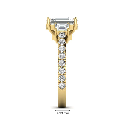 Emerald cut three stone lab grown diamond engagement ring in yellow gold featuring a 2.62 carat IGI certified center diamond with emerald cut side stones and pavé band.