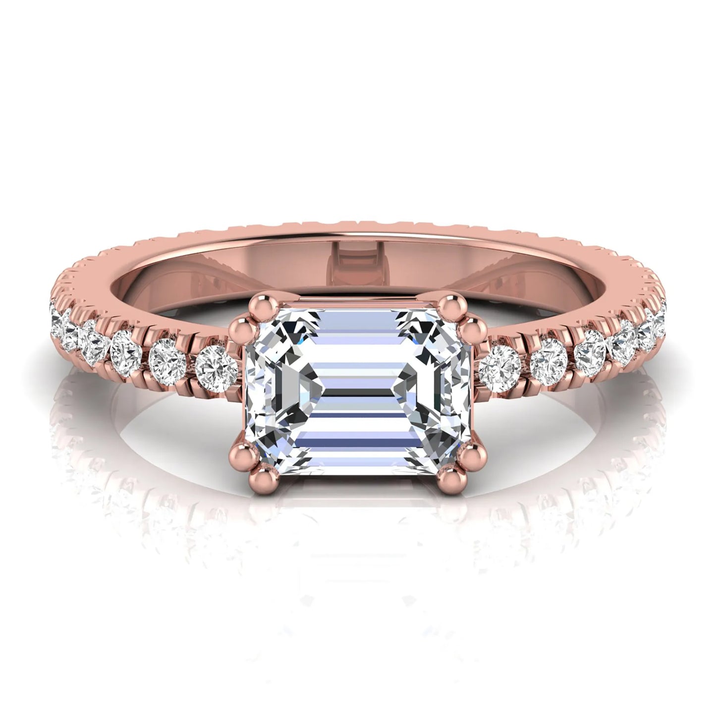 Emerald cut lab grown diamond side stone engagement ring featuring a four-prong setting with round accent diamonds in a rose gold tone design.