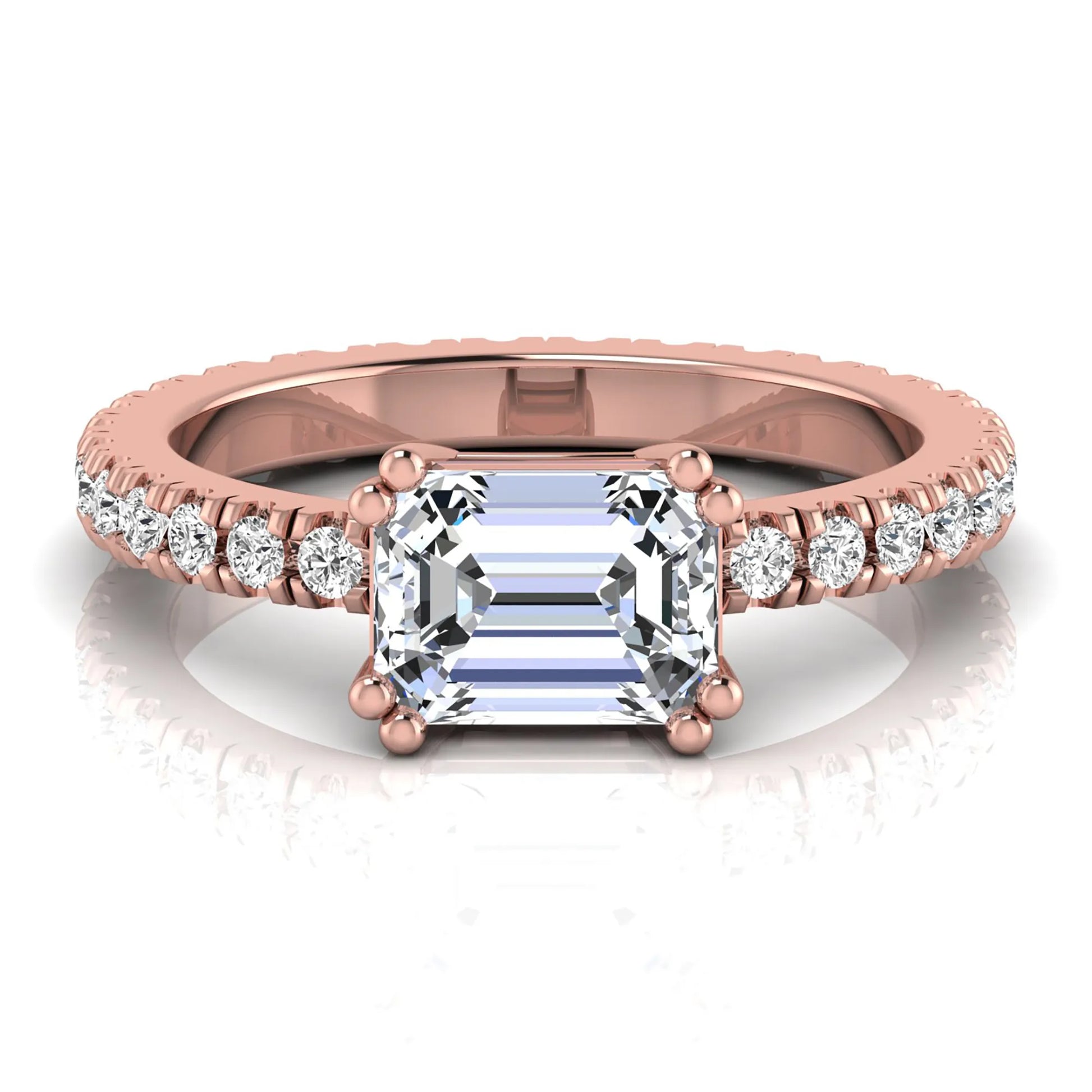 Emerald cut lab grown diamond side stone engagement ring featuring a four-prong setting with round accent diamonds in a rose gold tone design.