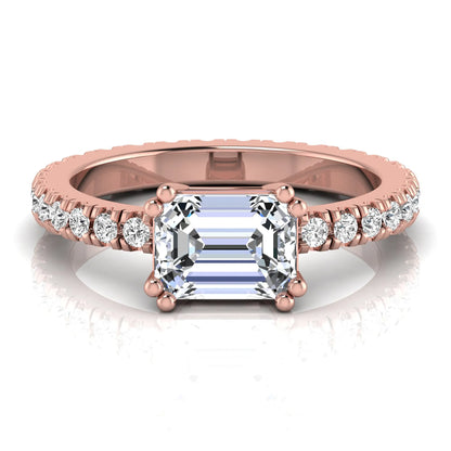 Emerald cut lab grown diamond side stone engagement ring featuring a four-prong setting with round accent diamonds in a rose gold tone design.