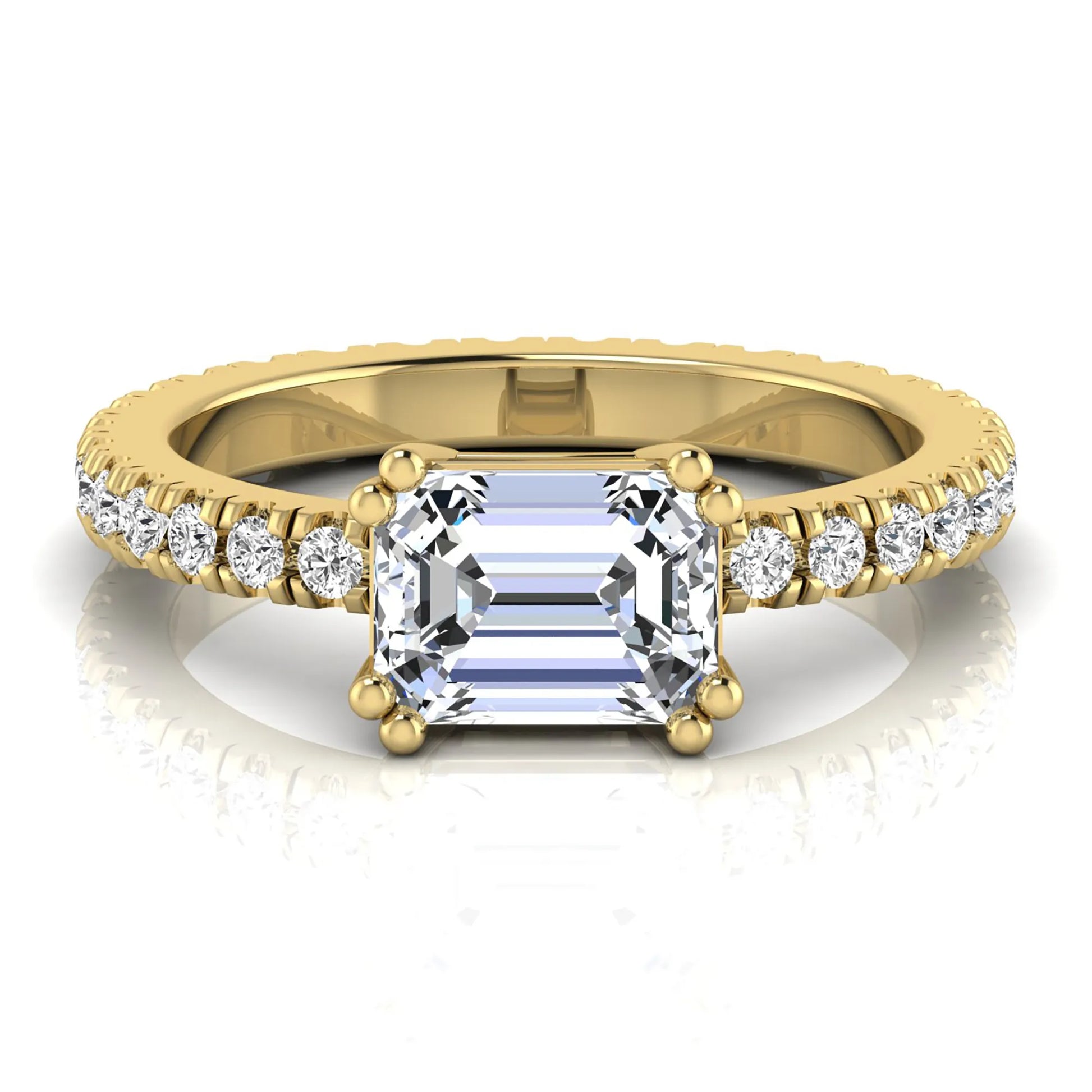 Emerald cut lab grown diamond side stone engagement ring featuring a four-prong setting with round accent diamonds in a yellow gold tone design.