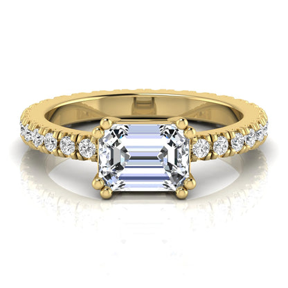 Emerald cut lab grown diamond side stone engagement ring featuring a four-prong setting with round accent diamonds in a yellow gold tone design.