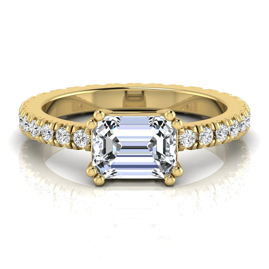 Emerald cut lab grown diamond side stone engagement ring featuring a four-prong setting with round accent diamonds in a yellow gold tone design.