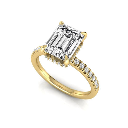 Emerald cut lab grown diamond engagement ring featuring a hidden halo, pavé diamond band, and four-prong setting in yellow gold tone.