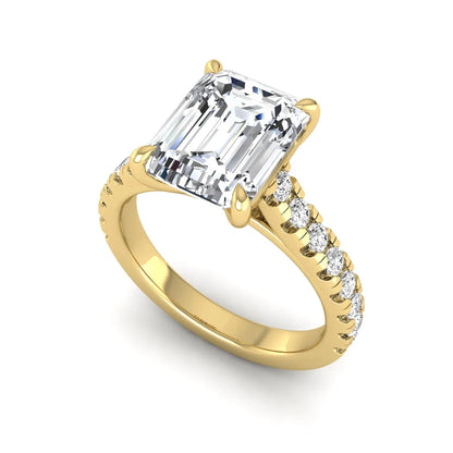 Emerald cut lab grown diamond engagement ring with pavé round diamonds in a yellow gold four-prong cathedral setting