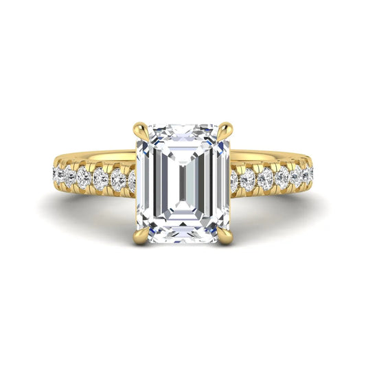 Emerald cut lab grown diamond engagement ring with pavé round diamonds in a yellow gold four-prong cathedral setting