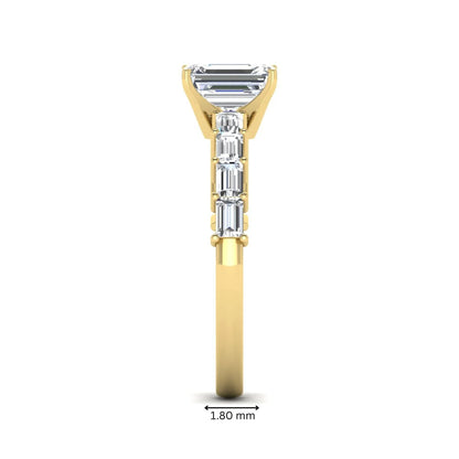 Emerald cut lab grown diamond engagement ring with baguette side diamonds in a four-prong solitaire accent setting and yellow gold tone band.