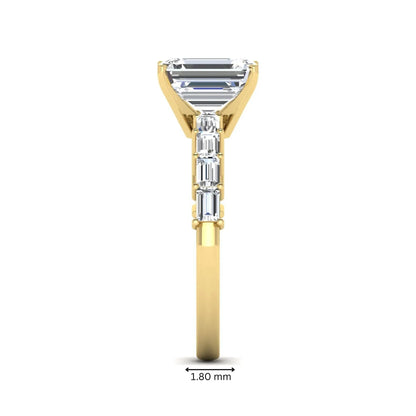 Emerald cut lab grown diamond engagement ring with baguette side diamonds in a four-prong solitaire accent setting and yellow gold tone band.
