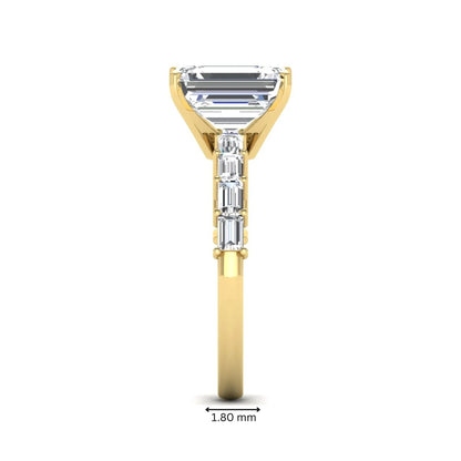 Emerald cut lab grown diamond engagement ring with baguette side diamonds in a four-prong solitaire accent setting and yellow gold tone band.